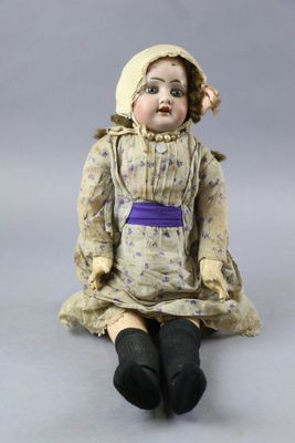 a doll that is sitting on the ground with a hat on