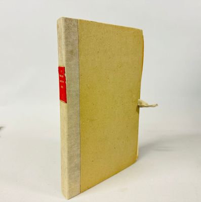un vieux livre portant une étiquette rouge, posé sur une surface blanche