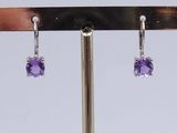 a pair of amethorate earrings on a metal stand