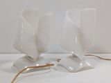 two white lamps that are on a white table