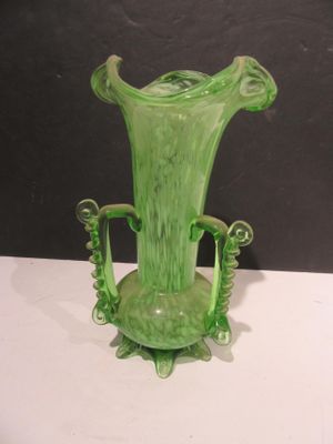 a green glass vase sitting on a white table