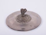 une assiette en argent ornée d'un oiseau sur fond blanc