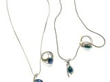 two silver necklaces with blue stones on a white background