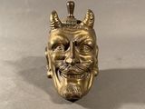 brass statue of a man ' s face with horns and a crown