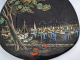 a black plate with a painting of boats on it