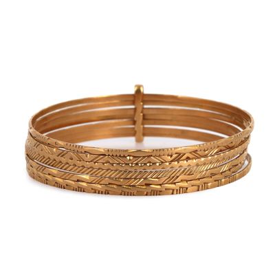 un gros plan sur une pile de bracelets en or sur fond blanc