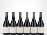 four bottles of red wine lined up on a table