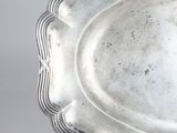 a silver plate with a decorative edge on a table