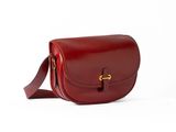 un sac en cuir rouge orné d'une boucle dorée sur fond blanc