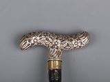 an old walking stick with a silver and black handle on a gray surface