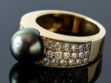an image of a black pearl and diamond ring on a black surface