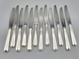 six silverplated knives and six knives on a table