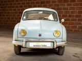 a small blue car parked in front of a brick wall