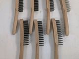 cinq peignes en bois avec des poils noirs sur un fond blanc
