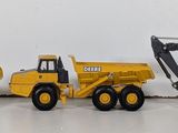 three toy construction vehicles that are lined up on a table