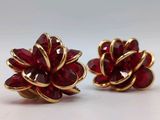 a pair of red and gold flower earrings on a white surface
