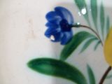 Gros plan sur une assiette ornée d'une fleur bleue