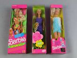 three barbie dolls are in their boxes on a gray surface
