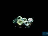 a close up of three different colored gems on a black surface