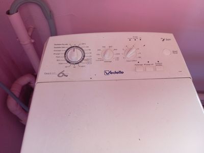 a washing machine that is sitting in a pink room