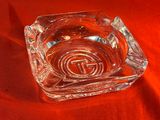 un cendrier en verre orné d'un logo, posé sur un tissu rouge