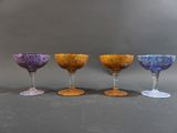 four wine glasses are lined up in a row on a gray surface