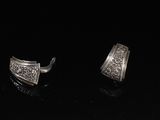 une paire de boucles d'oreilles en argent posées sur une surface noire