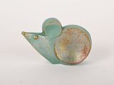 une petite figurine de souris verte et dorée posée sur une surface blanche