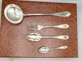 four silver spoons and two silver spoons on a brown place mat