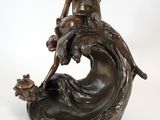 bronze statue of a woman sitting on a wave holding a fish