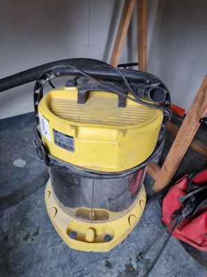 un aspirateur jaune posé par terre à côté d'un sac rouge