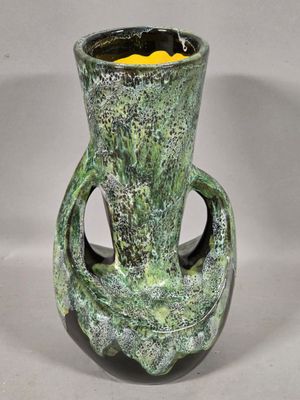 a green vase with a yellow flower inside of it