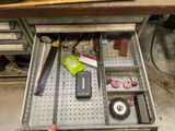 un tiroir métallique contenant des outils, posé sur un établi