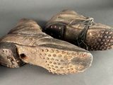 pair of old worn leather shoes with holes on them on a gray surface