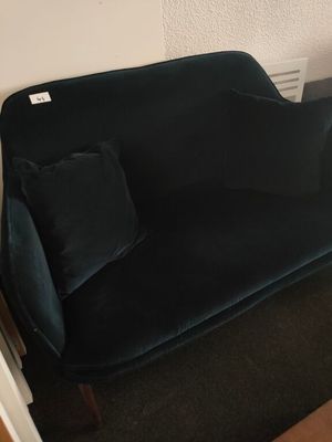 black velvet sofa in a corner of a room next to a wall