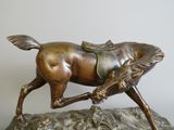 bronze statue of a horse with a saddle on a rock
