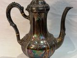 silver plated coffee pot with ornate handle on white background