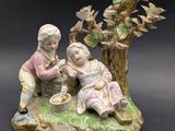une figurine représentant un garçon et une fille assis sous un arbre