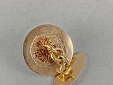a close up of a gold pin with a chain on it
