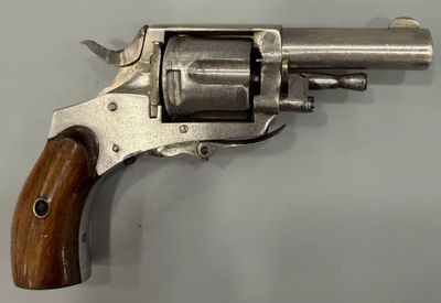 un vieux revolver avec une poignée en bois sur une surface blanche