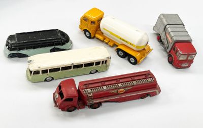 cinq camions miniatures et un bus posés sur une surface blanche