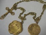 deux colliers en or avec une croix et un médaillon suspendus à une chaîne