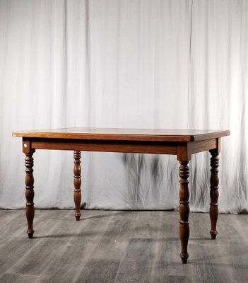 La table est en bois et possède des pieds tournés.