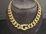 un collier à chaîne en or et un chapeau exposés dans une vitrine