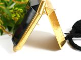a black stone on a gold plated necklace with a black cord