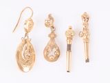 three pairs of gold earrings and a pen on a white surface