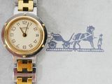 a gold and silver watch with a horse drawn sleigh in the background