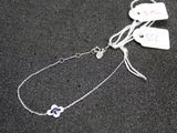 a silver bracelet with a heart on it on a black surface