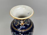 a blue and white vase with a gold decoration on it