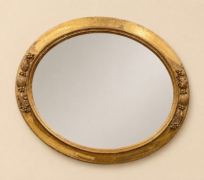 une image représentant un miroir rond accroché au mur, avec un cadre doré